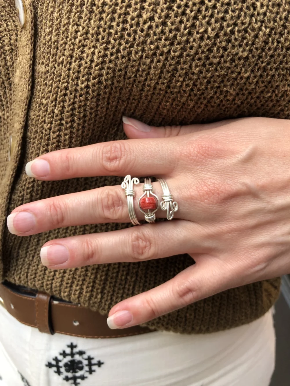 Main qui porte une bague argentée avec une pierre rouge
