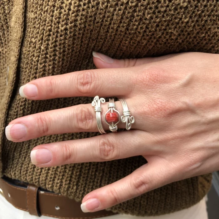 Main qui porte une bague argentée avec une pierre rouge