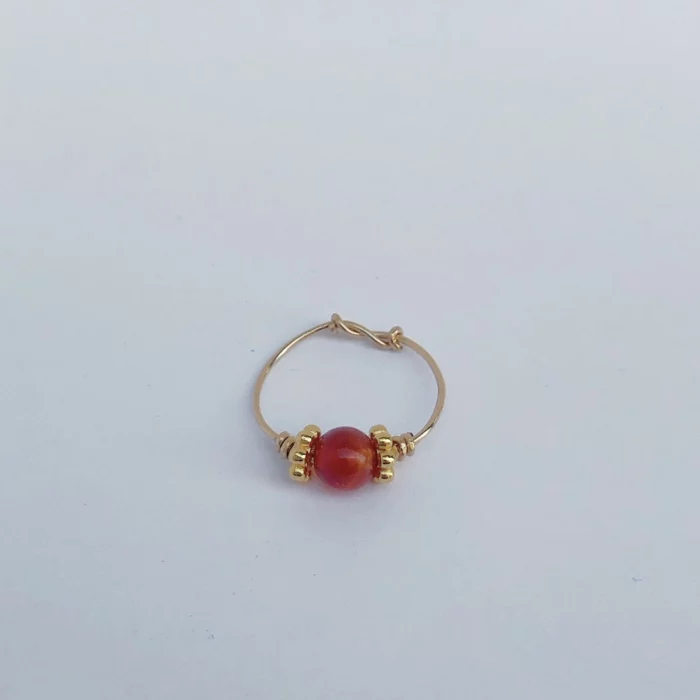 Bague fine dorée avec une pierre rouge