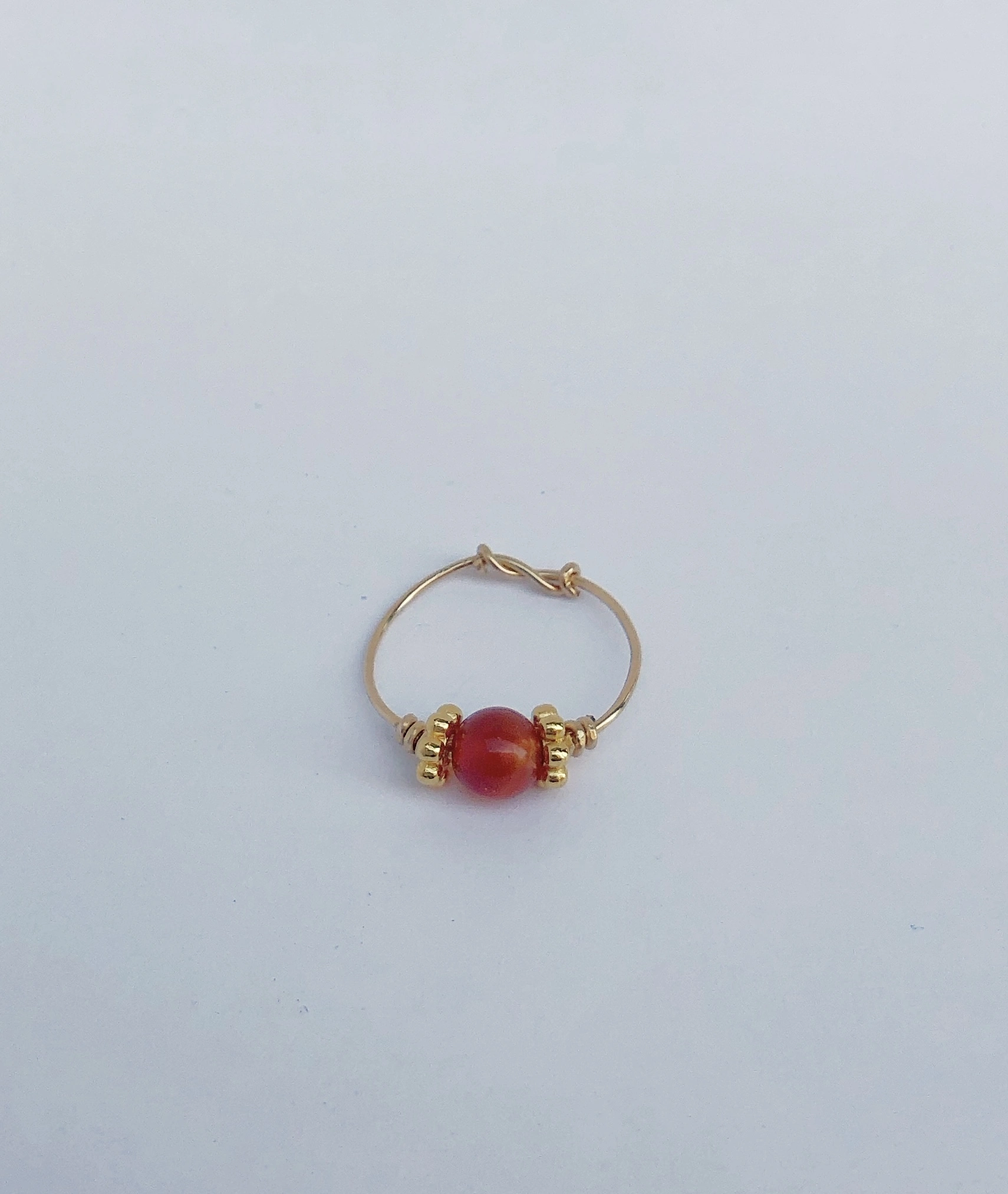 Bague fine dorée avec une pierre rouge