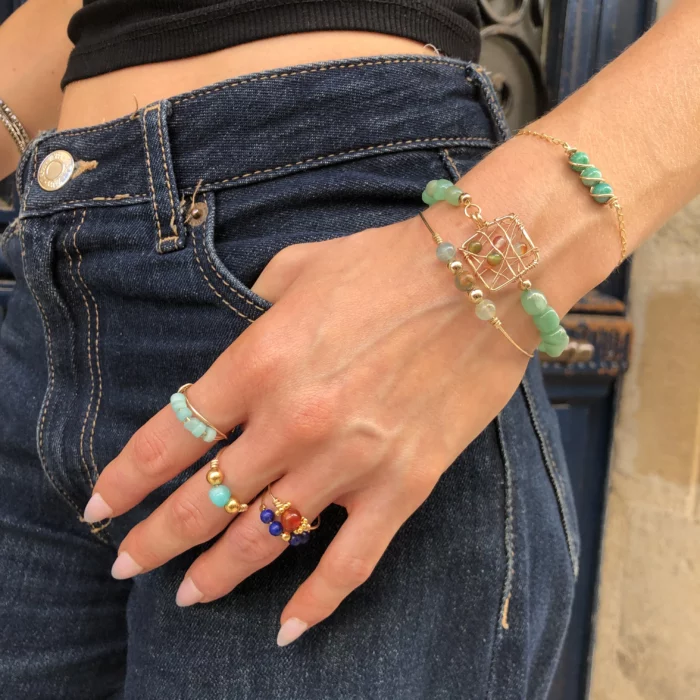 Main de femme avec différents bijoux dorés (bagues et bracelets)