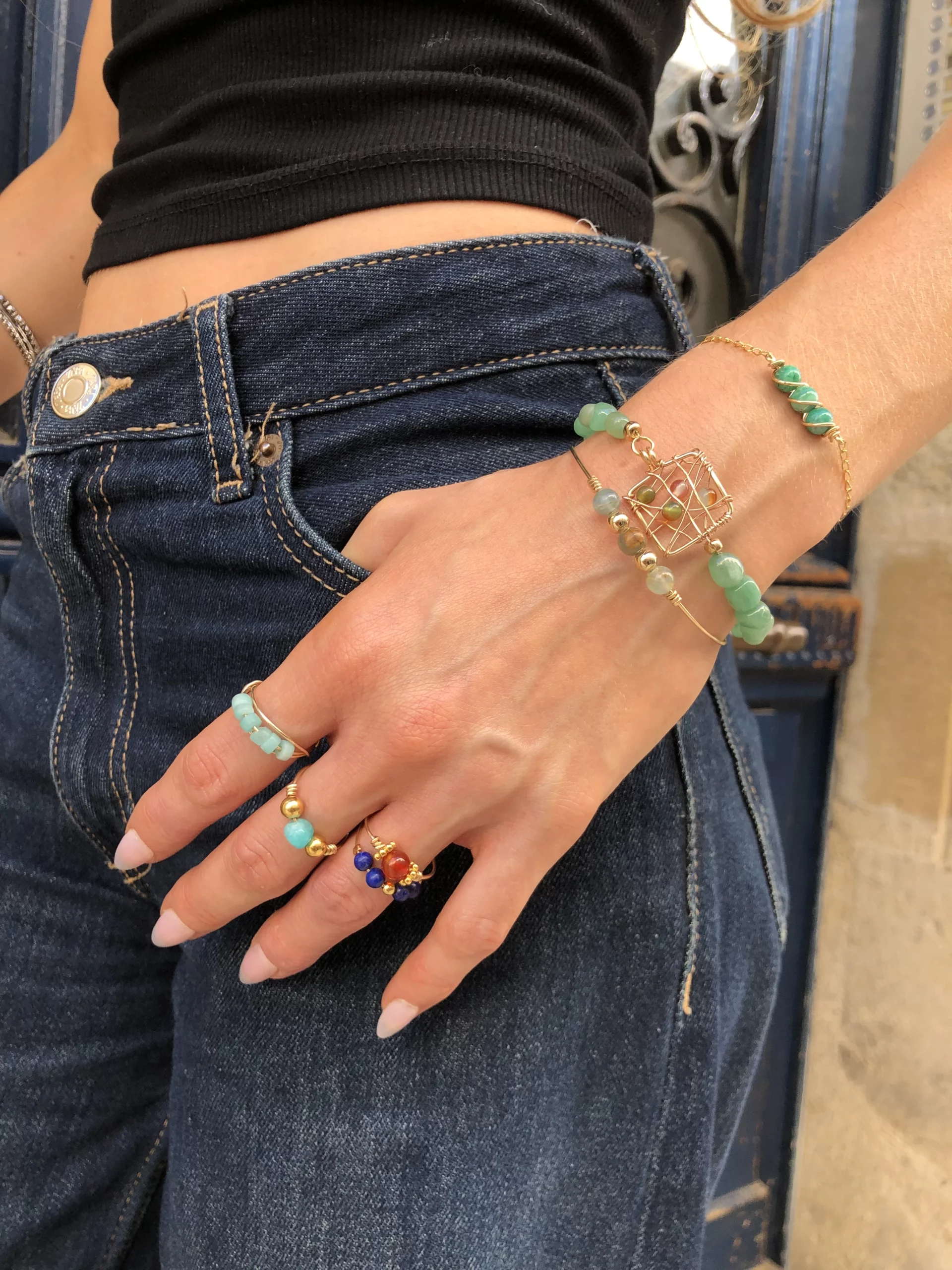 Main de femme avec différents bijoux dorés (bagues et bracelets)