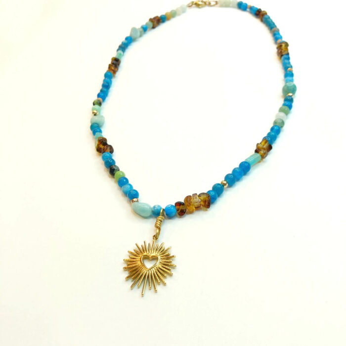 Collier en en petites perles blues avec un pendentif cœur rayonnant