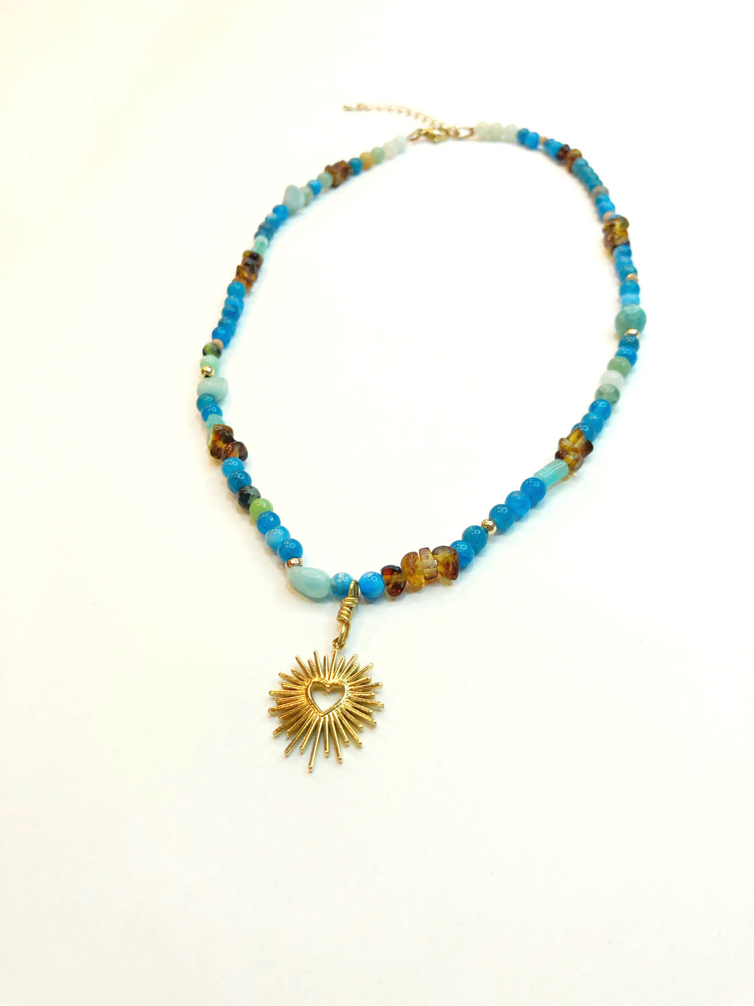 Collier en en petites perles blues avec un pendentif cœur rayonnant